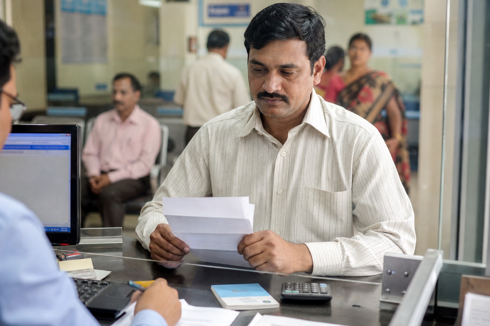 Indian adult at a bank desk with an FD advice letter, a passbook, and a calculator